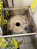 Mop sink with visible gaps around drain and wall joints causing water leakage.
