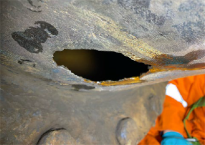 A steel pipe with a corroded hole at the bottom