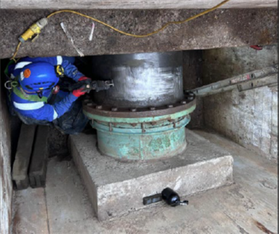 A man grinding away the dirt around the steel pipe to get surface ready