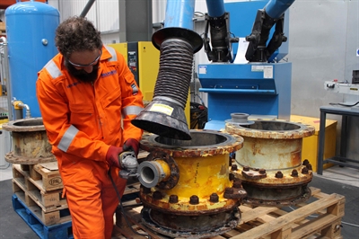 A man wearing PPE using a power tool on the spool