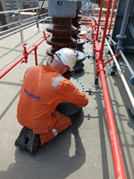 A man wearing protective clothing is kneeling in front of the repair, applying a coating