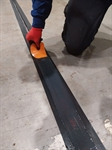A man is using a spatula to smooth the liquid in the join to match profile of concrete floor
